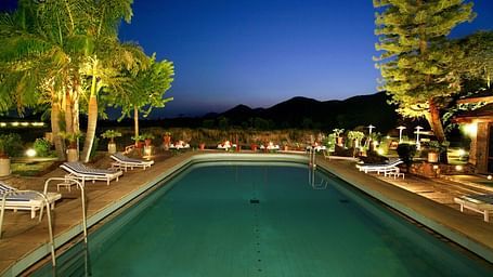 A swimming pool at Shikarbadi Hotel illuminated with lights