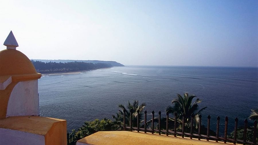 A panoramic view of a wide bay or estuary, with calm blue water reflecting the sky. 