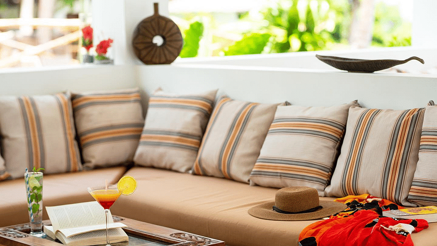 Close-up of a cushioned seating area with a hat placed on the sofa and a drink placed on the table - Shooting Star Boutique Hotel.