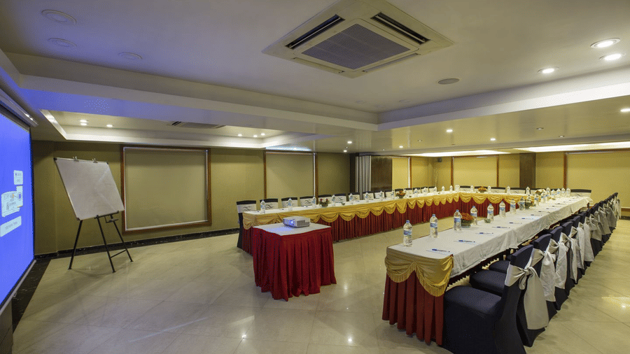 Conference room at The Citrine, Bangalore, in U-shape with yellow, and maroon table skirts, projector, flip chart and chair sashes.