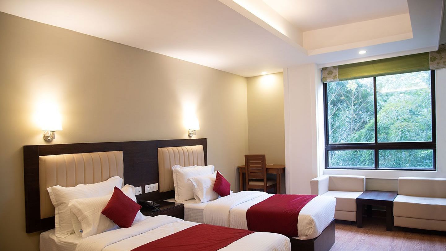 A hotel room in Gangtok featuring twin beds, warm lighting, and a window offering stunning views - Summit North Star, Gangtok