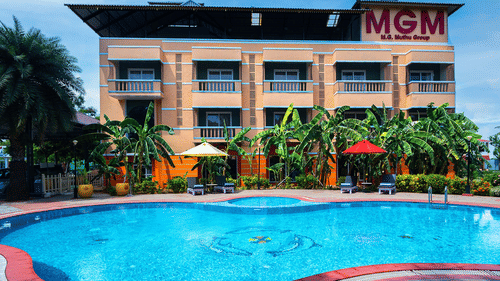 Front view of MGM hotel with a swimming pool surrounded by palm trees.