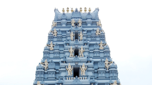 A grand, towering stone gopuram entrance to a traditional South Indian temple complex.