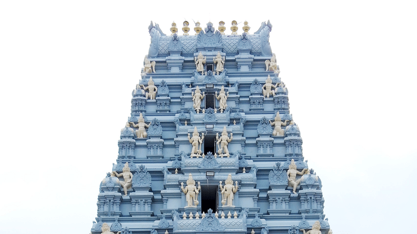 A grand, towering stone gopuram entrance to a traditional South Indian temple complex.