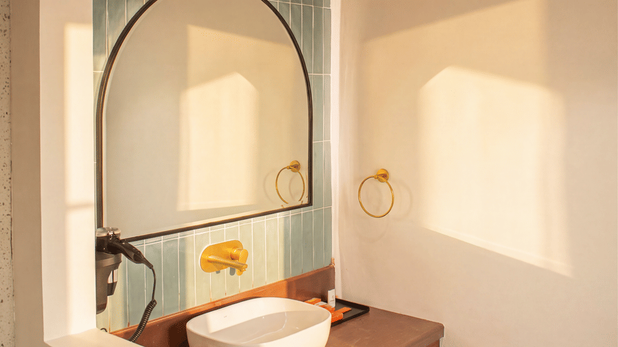 A close-up view of a bathroom vanity with a white washbasin, an arched mirror, and a wooden countertop at The Sierra - By The Lake.
