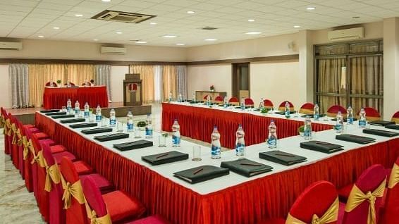 A conference room arranged with tables in a u-shape, covered in red cloths - Lion Lords Inn Rajula
