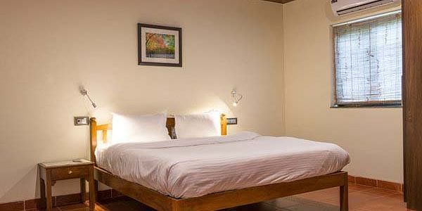 A bedroom with a wooden bed frame, white linens, and a small picture on the wall.