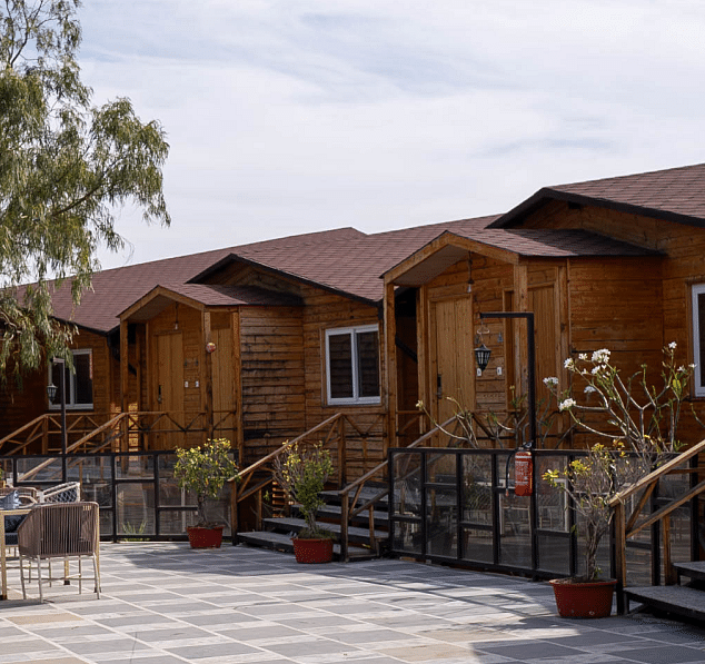 A row of wooden cabins with roofs and windows.- Bamboo Saa Resort & Spa, Udaipur.