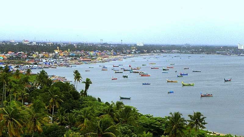 Aerial view of the beach with surrounding trees and fishing boats scattered across the water
