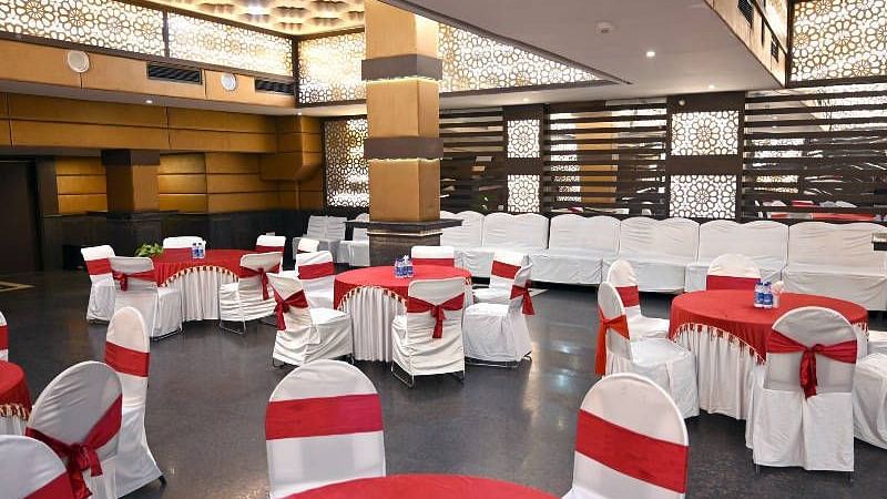 An expansive conference hall with several round tables along with chairs surrounding it at Hotel Gold, Panipat.