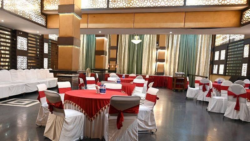 A beautiful conference hall with elegant lights in the ceiling featuring round tables set up all across the hall at Hotel Gold, Panipat.