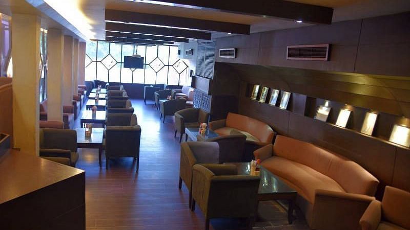 A cosy seating area with rustic interiors and brown leather couches - Hotel Gold, Panipat