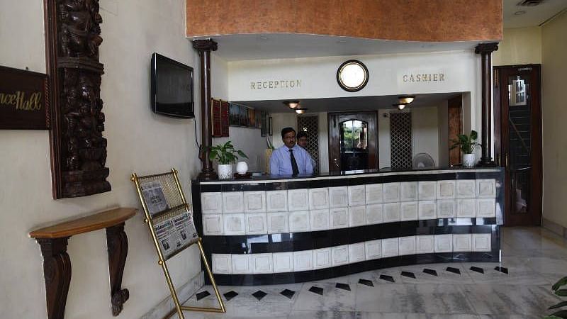 Front view shot of the reception desk at Hotel Gold, Panipat with a staff member standing behind it.