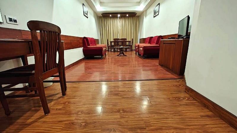 The living room of the Suite featuring a shiny wooden flooring along with red coloured couch set in the end - Hotel Gold, Panipat
