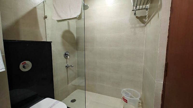 A bathroom featuring a full size bathtub along with a commode separates by a glass partition in the Suite - Hotel Gold, Panipat