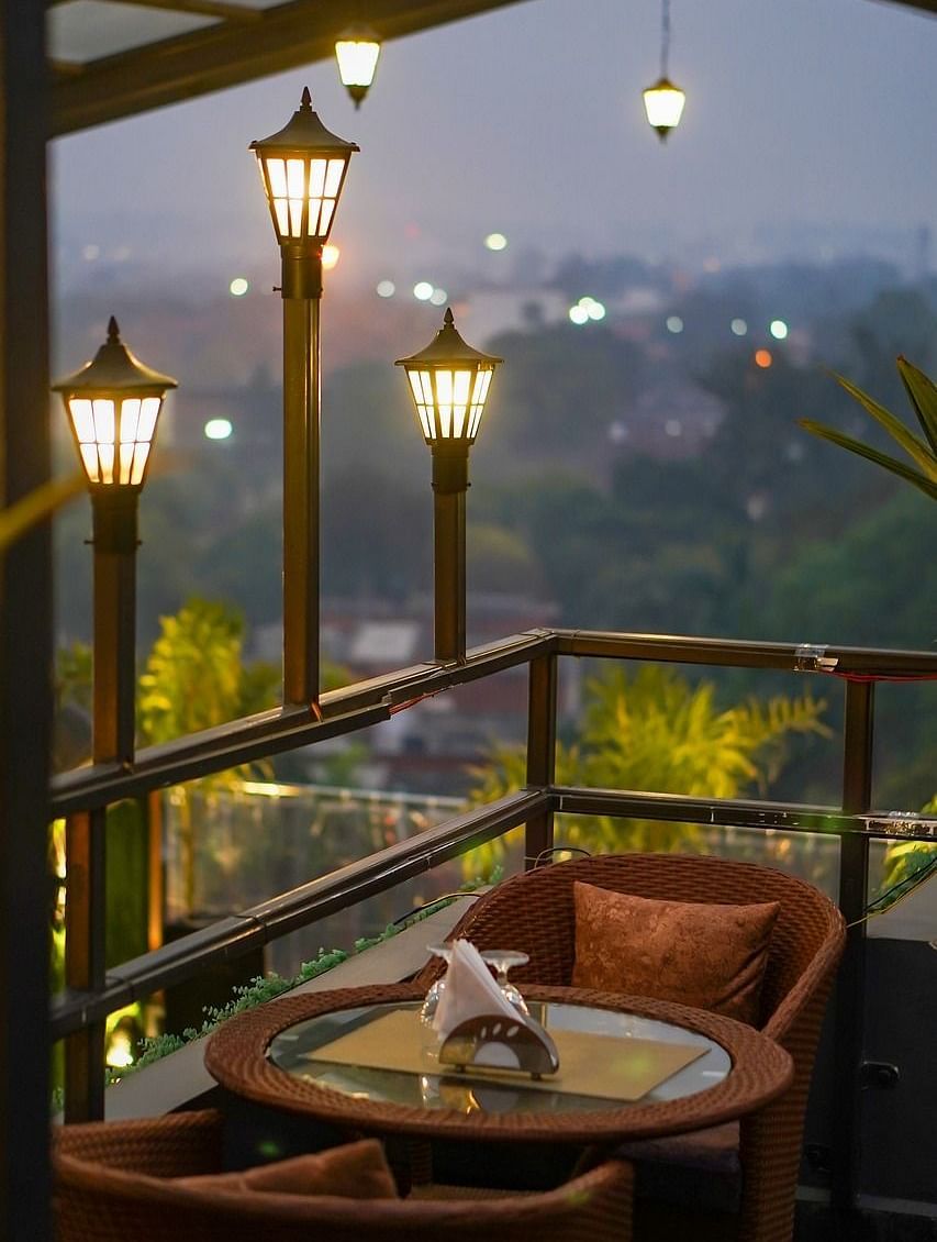 Two chairs facing each other on a terrace with warm lights beside it on a late evening.
