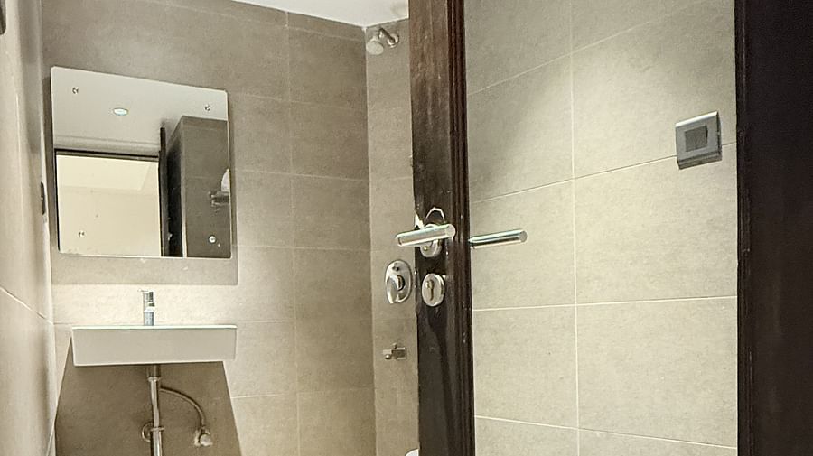 A spacious washroom with a wall-mounted mirror above the washbasin and an open door for entry | Cenneys Gateway