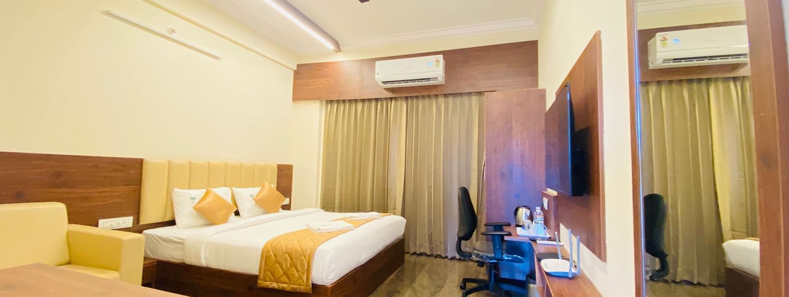 Well-furnished room with queen bed, sofa, and study space for a relaxing stay at Hotel Sahara Tree.