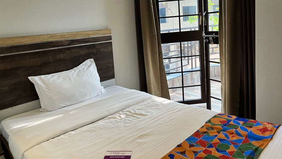 A close up shot of a bed near a window in our hotel room at VITS Select Kharadi, Pune.