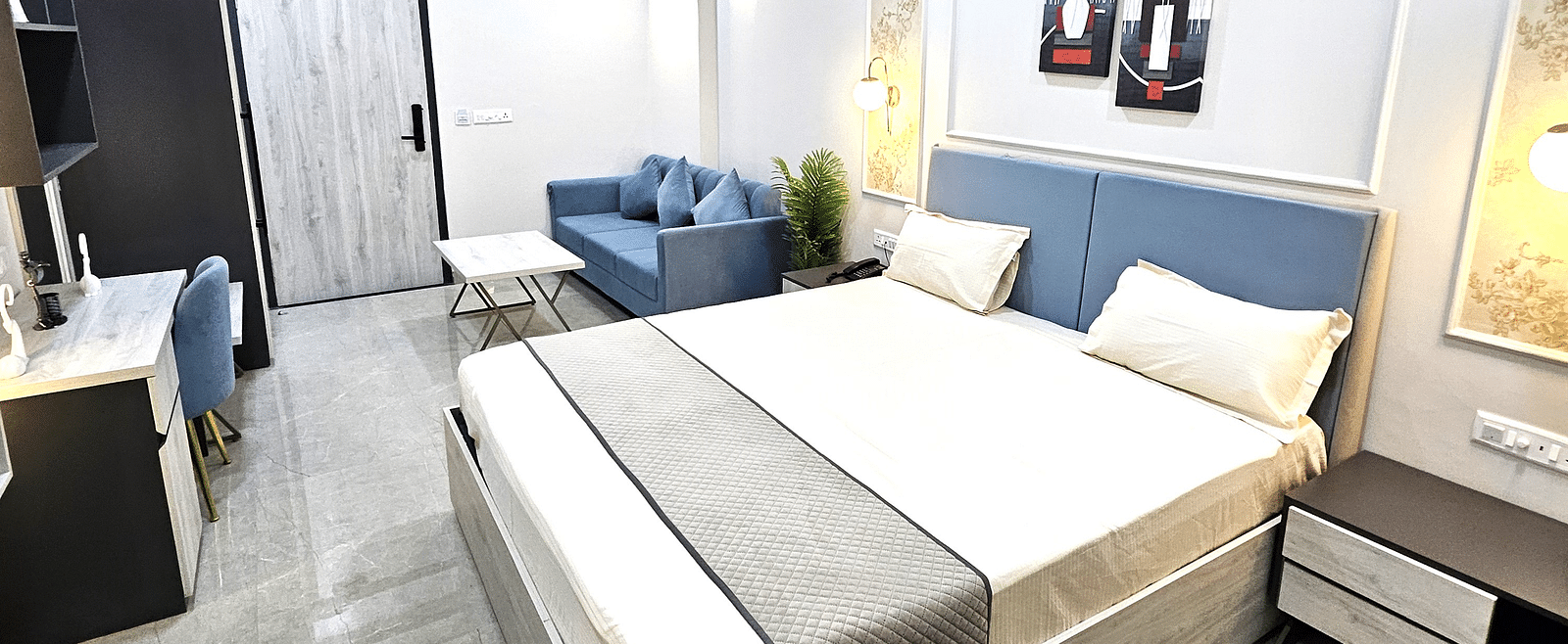 Spacious and elegantly designed studio room featuring a plush bed with a soft headboard, a cosy seating area with a modern sofa, a sleek work desk, and stylish décor - Urban Suites by BluSalzz, Jaipur
