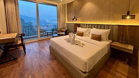 Elegant bedroom with large windows, wooden accents, and a scenic balcony view – ARNISA Boutique Hotel