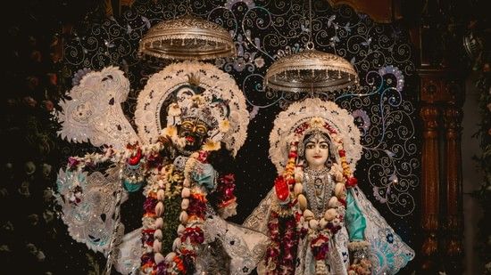 Two majestic garlanded idols of Krishna & Radha in a temple.