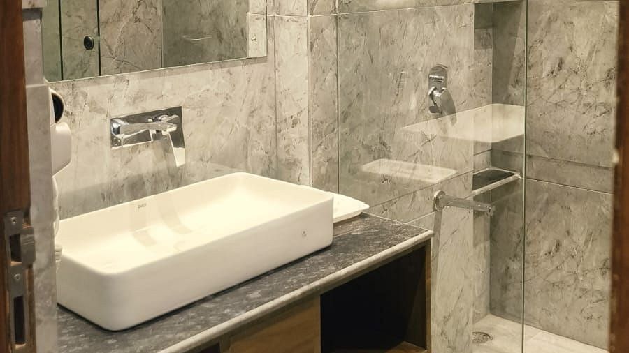 Bathroom of Superior Forest View Room at Silver Sand Sea Princess Beach Resort with a sleek countertop basin, large mirror, open storage shelf, and a glass-enclosed shower area with a rainfall showerhead