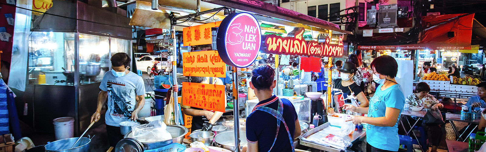 a person buying food from a vendor selling street food in Bangkok.