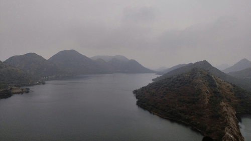 Misty landscape with a winding river and distant mountains.