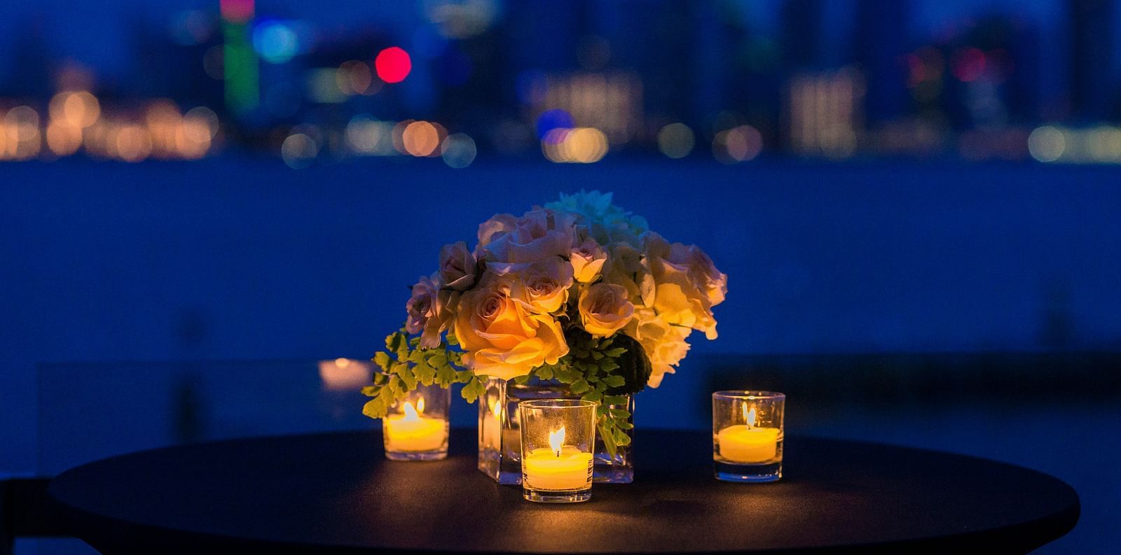 An intimate table setting with candles, overlooking a city skyline at dusk at Ramoji Film City in Hyderabad 