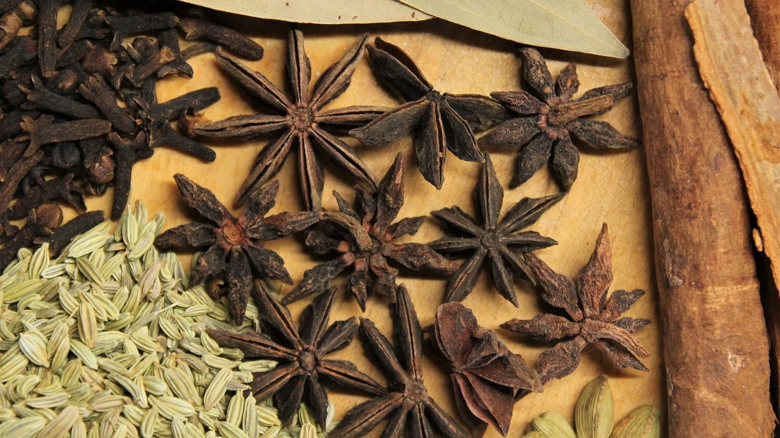 An image featuring a variety of Indian spices, including cardamom, star anise, cinnamon, bay leaves, and cloves.