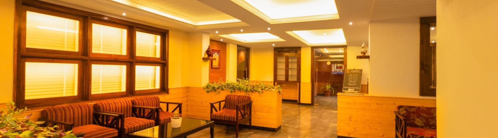 Bright lounge with wooden interiors and cosy chairs at Sumitel Premier Inn, Siliguri.