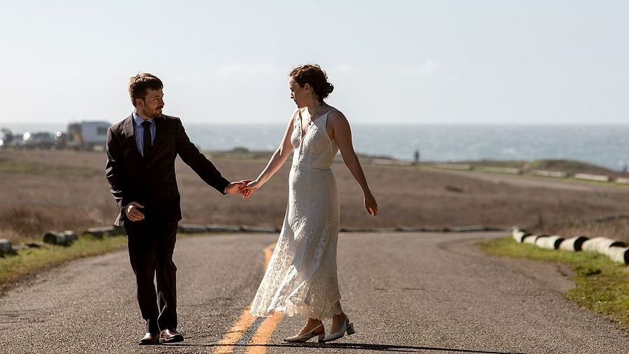 Couple holding hands while walking down a road glowing in the evening light