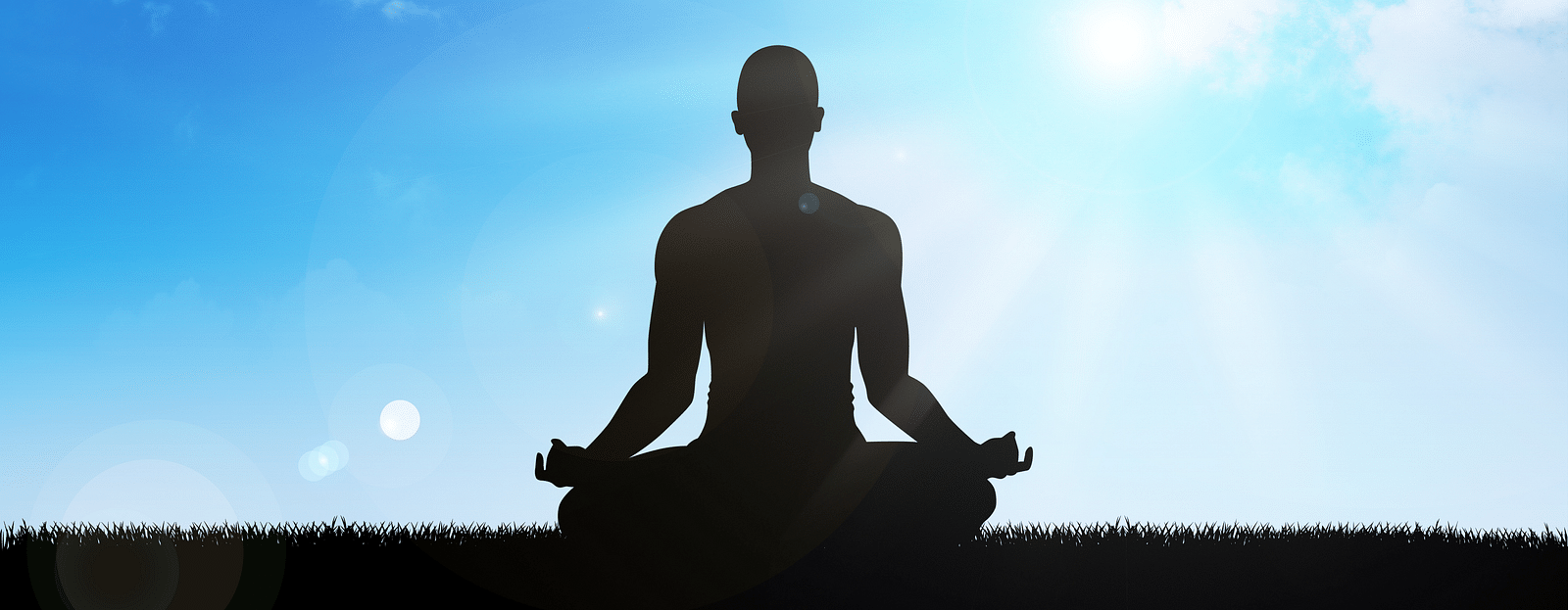 Person meditating on a mountaintop with a sunrise in the background.