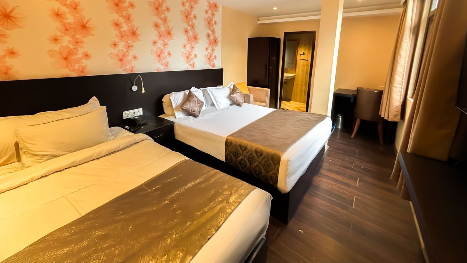 A bedroom with two queen size beds, a wardrobe, a table, and a chair at Avianna Hungry Jack, Gangtok.