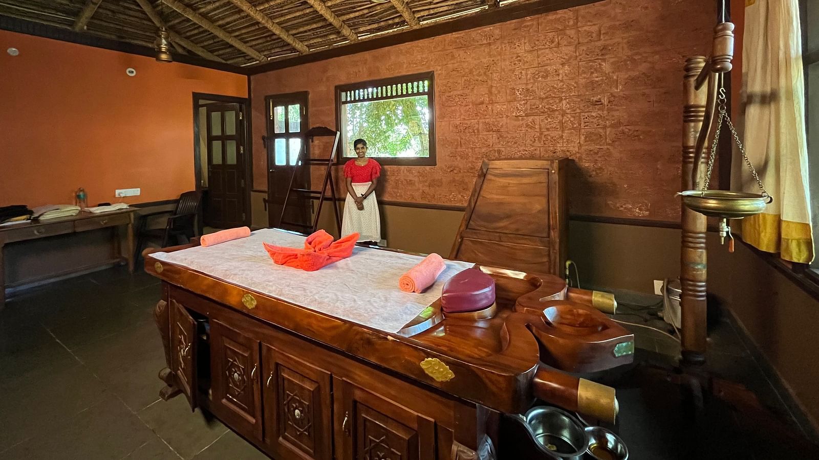 interior of the ayurveda spa with a wooden bed with soft towels in the middle with enchanting aromoas of incess sticks at hoysala village resort in hassan