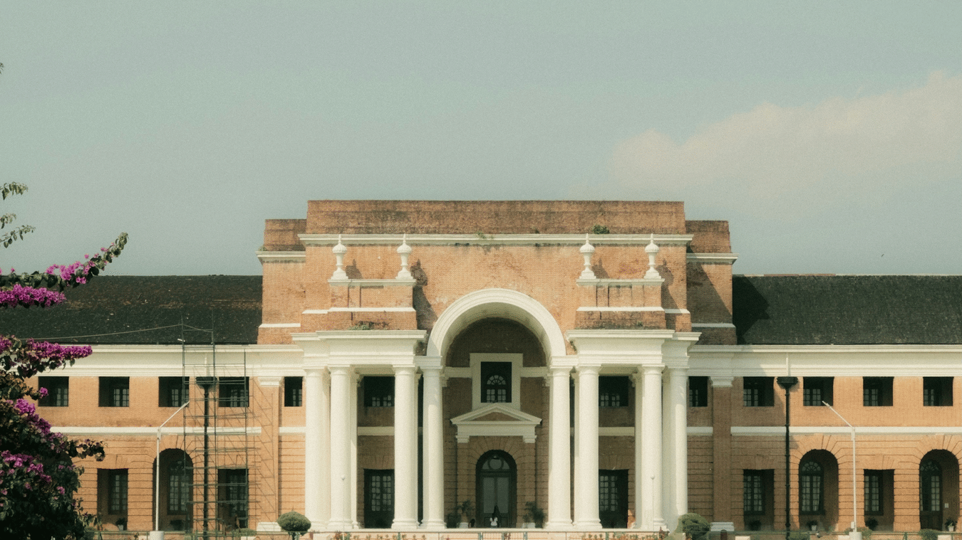 Facade of the Forest Research Institute, one of the top tourist places in Dehradun, Uttarakhand, with manicured lawns in between a pathway leading to the entrance.