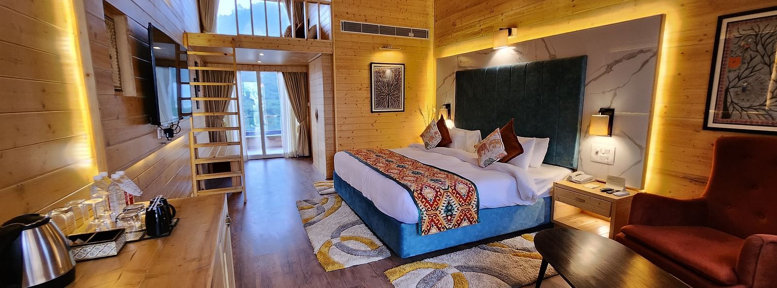 A cosy room with wooden paneling, a plush bed, and warm lighting. A ladder leads to a loft area. - Bamboo Saa Resort & Spa, Udaipur