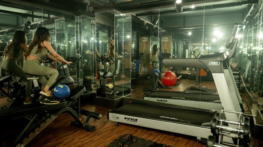 Fitness centre at The West Gate Posada By Summit, Darjeeling, equipped with a treadmill, exercise bike, weights, and mirrors.