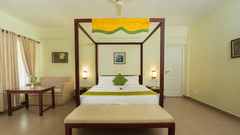 A bedroom features a four-poster bed and a bench, creating a cosy atmosphere.- Abad Brookside Lakkidi, Wayanad