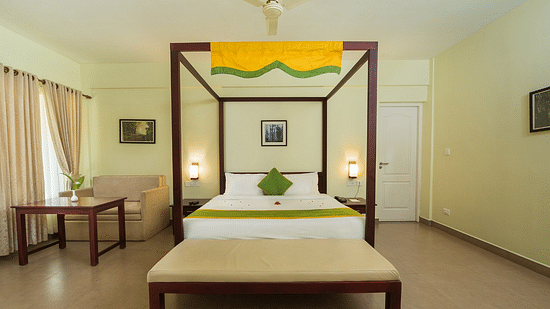 A spacious bedroom with a four-poster bed, elegant furnishings, and airy interiors. - Abad Brookside Lakkidi, Wayanad