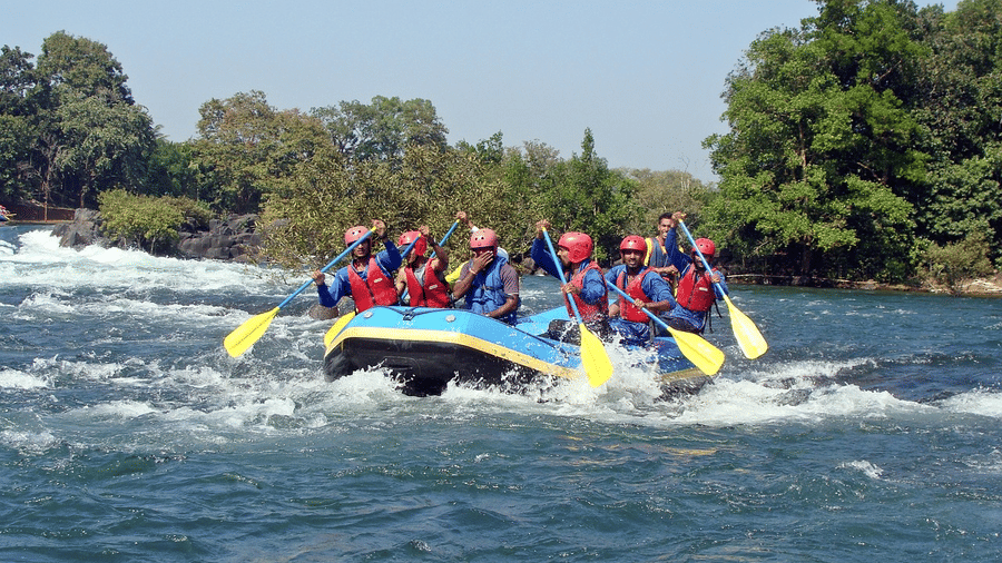 A group of adventurers in life jackets, joyfully rowing together in their raft on a scenic river, surrounded by nature.