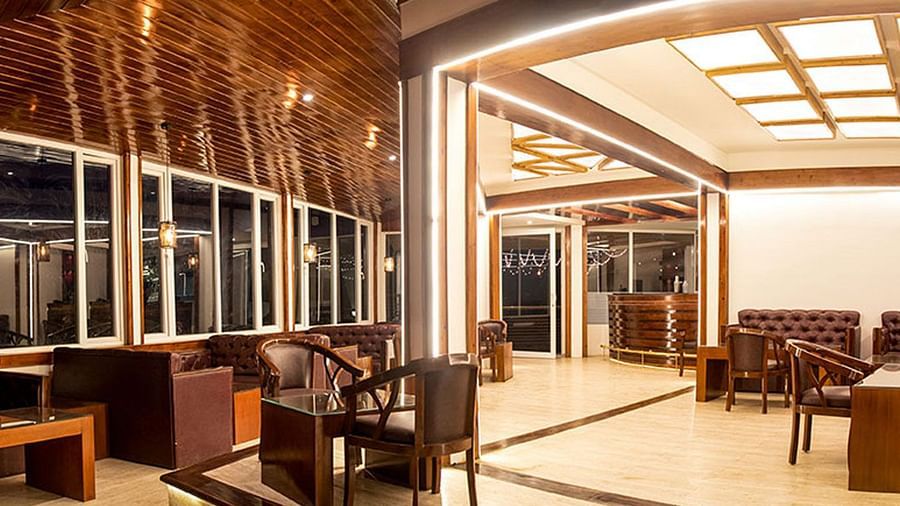 a wide angle shot of a bar featuring leather couches, lit by warm lighting - Summit North Star, Gangtok