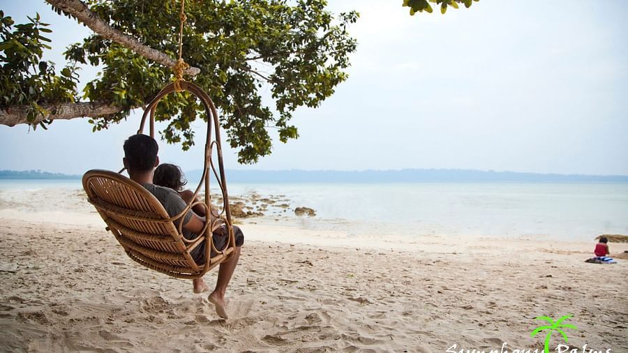 A person with a child on a swing resting at the beach