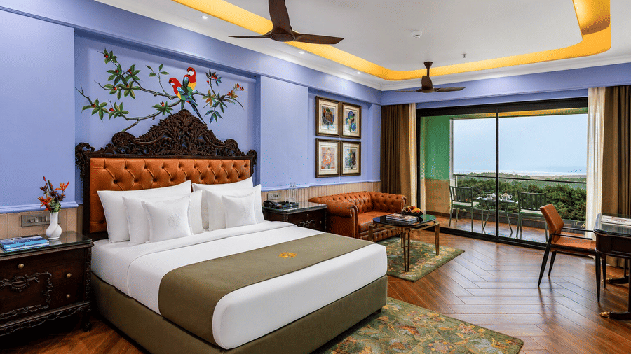 A neatly-made bed, a seating area and a balcony with sea views in a Premium Sea View Room at MAYFAIR Bay Resort, Paradeep.