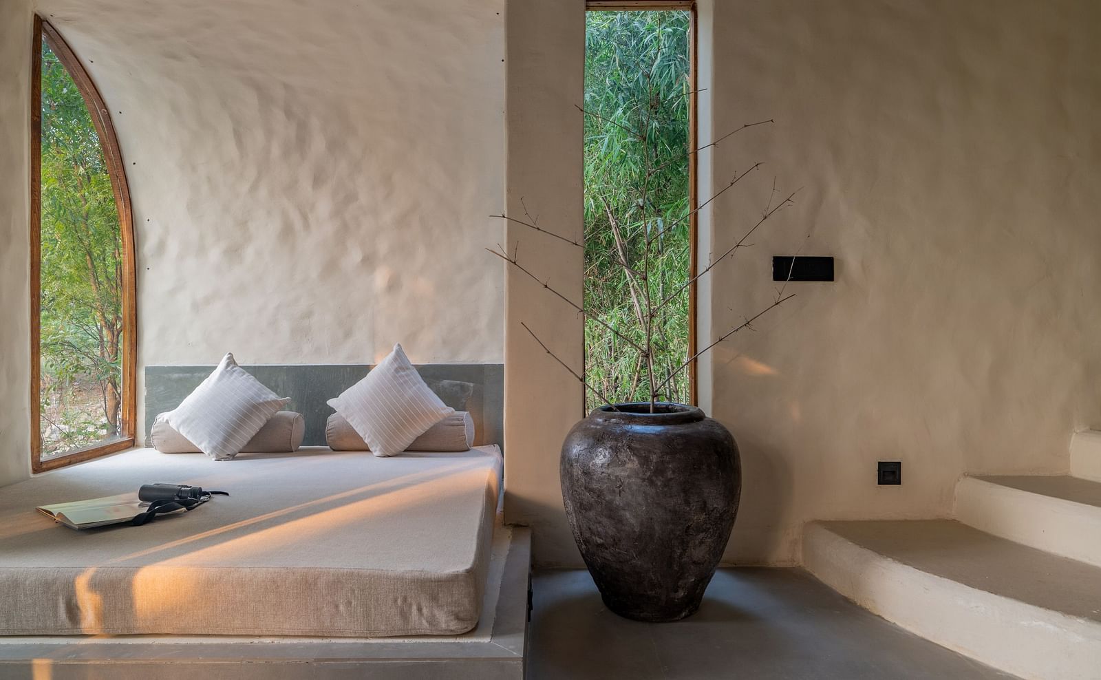 Built-in cushioned seating by a tall arched window with soft natural lighting.
