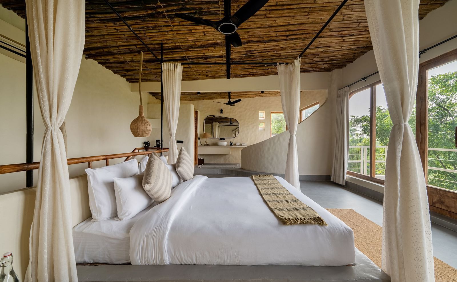 Bedroom with canopy bed, large windows, wooden ceiling, and serene outdoor views.