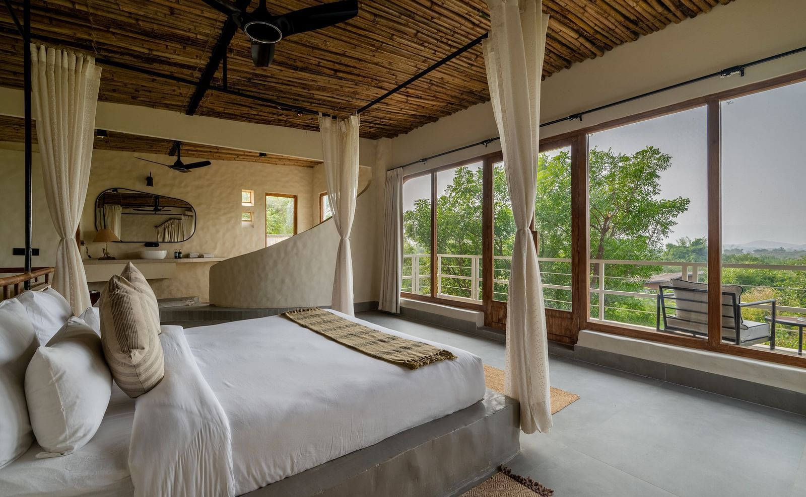 Bedroom with canopy bed, large windows, wooden ceiling, and serene outdoor views.