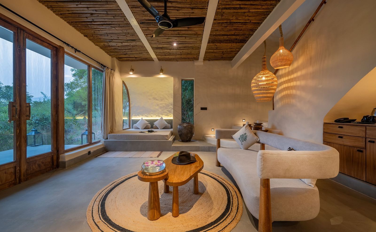 Close-up of a bedside area with a warm lamp, cushioned seating, and natural decor.