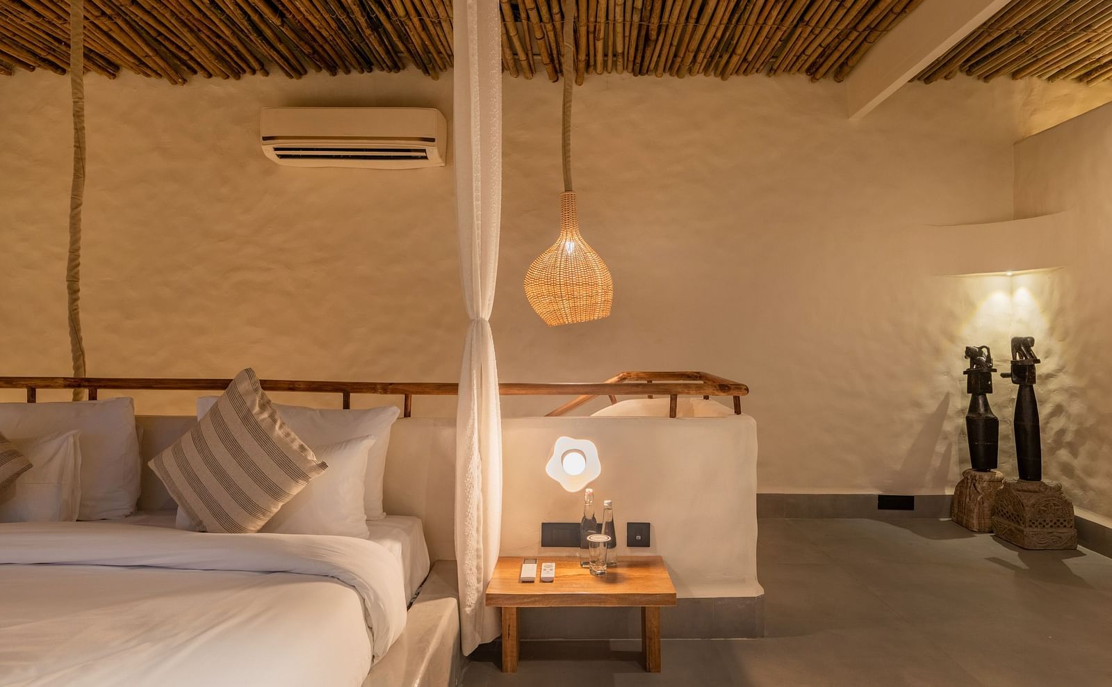 Cosy bedroom with a bedside lamp, natural decor, and cushioned seating along the wall.